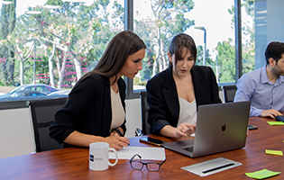 Dos alumnas miran la pantalla del ordenador juntas en una sala