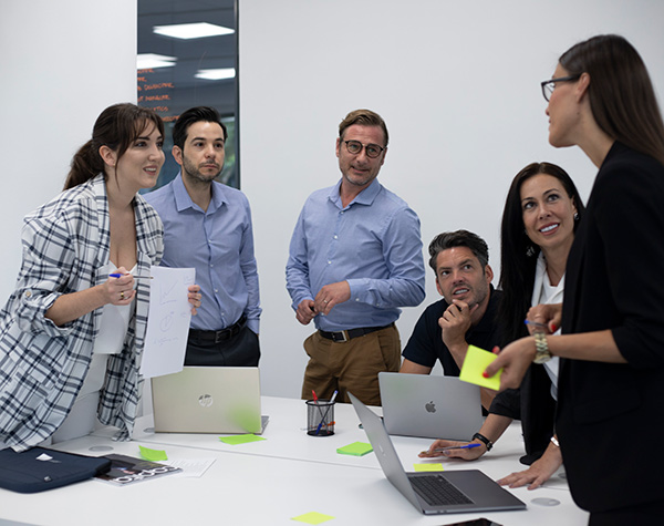 Seis alumnos charlando en clase del master online con ordenadores